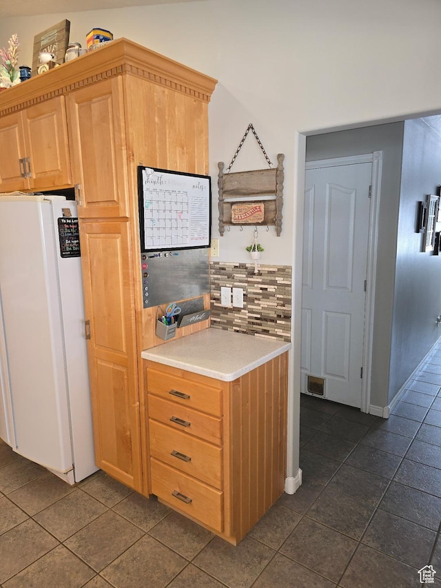 kitchen featuring visible vents, dark tile patterned floors, light countertops, freestanding refrigerator, and backsplash