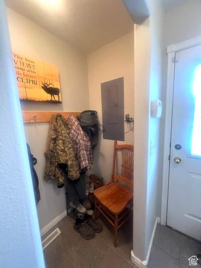 interior space featuring tile patterned floors, visible vents, baseboards, and electric panel