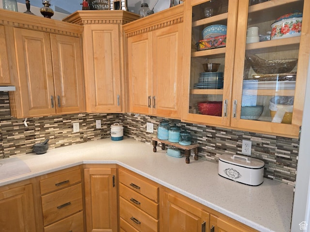 kitchen featuring glass insert cabinets, light brown cabinets, and backsplash