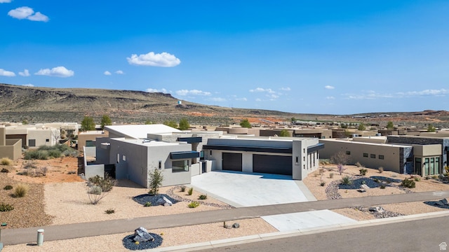 view of front facade featuring stucco siding, a garage, a mountain view, and concrete driveway