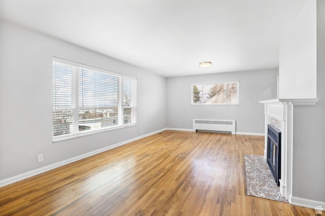 2928 S 575 W, Bountiful, UT 84010 - unfurnished living room featuring a fireplace with flush hearth, baseboards, radiator heating unit, and light wood finished floors