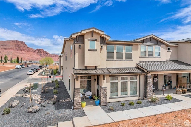 view of front of house with metal roof, stucco siding, stone siding, and a mountain view