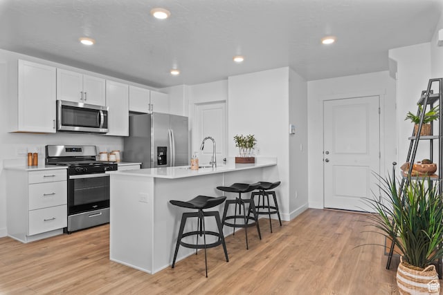 1596 S 3740 E Unit 1358, Spanish Fork, UT 84660 - kitchen with appliances with stainless steel finishes, a sink, a breakfast bar area, light wood finished floors, and recessed lighting