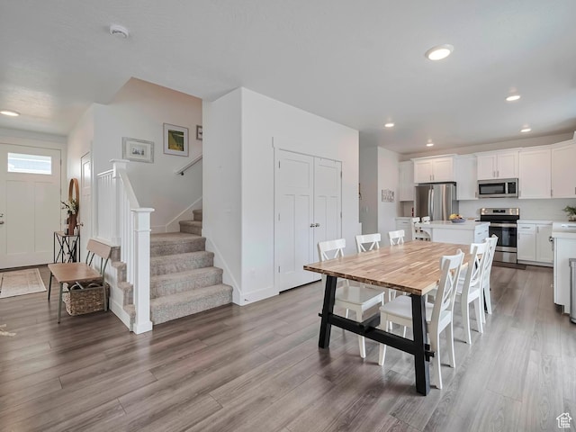 dining room with stairs, wood finished floors, baseboards, and recessed lighting
