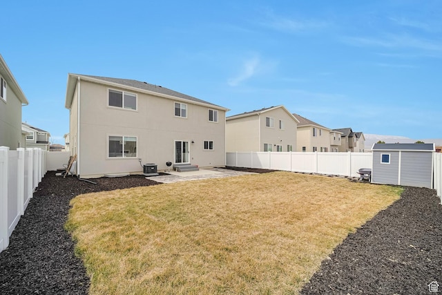 rear view of house featuring a patio, a fenced backyard, a storage unit, an outbuilding, and a yard