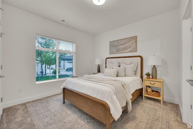bedroom with baseboards and light colored carpet