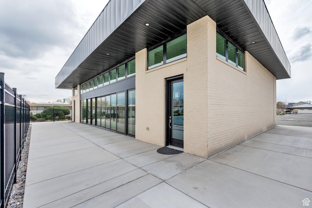 rear view of property featuring fence, brick siding, and a patio area