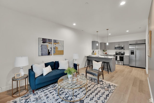 living area featuring baseboards, recessed lighting, and light wood-type flooring