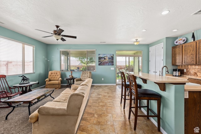3352 E Sweetwater Springs Dr, Washington, UT 84780 - kitchen with light countertops, a kitchen bar, baseboards, backsplash, and a ceiling fan