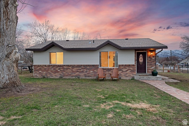 view of front of property featuring fence, brick siding, and a yard