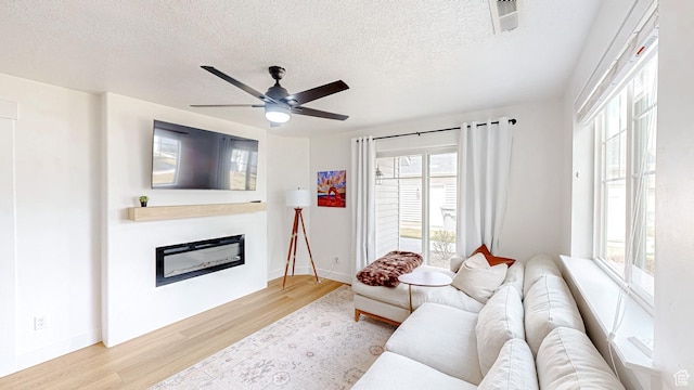 2527 W 500 S Unit 1, Springville, UT 84663 - living room featuring a textured ceiling, visible vents, a ceiling fan, a glass covered fireplace, and wood finished floors