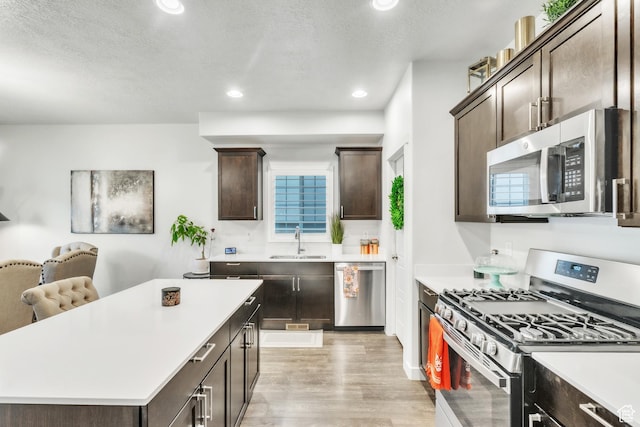 1710 S Prevedel Dr, West Haven, UT 84401 - kitchen with light countertops, light wood-type flooring, a sink, dark brown cabinets, and appliances with stainless steel finishes