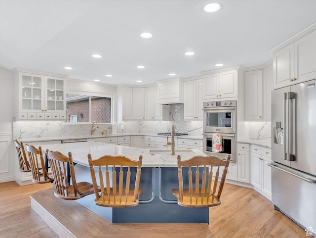 kitchen featuring stainless steel appliances, light stone countertops, and white cabinetry