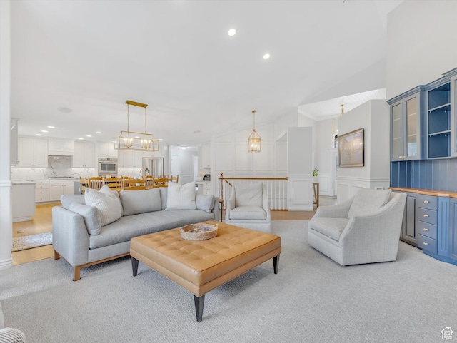 living room with a wainscoted wall, a decorative wall, recessed lighting, and lofted ceiling