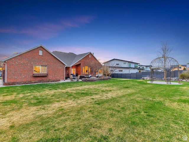 rear view of house featuring fence, a patio, a lawn, and brick siding