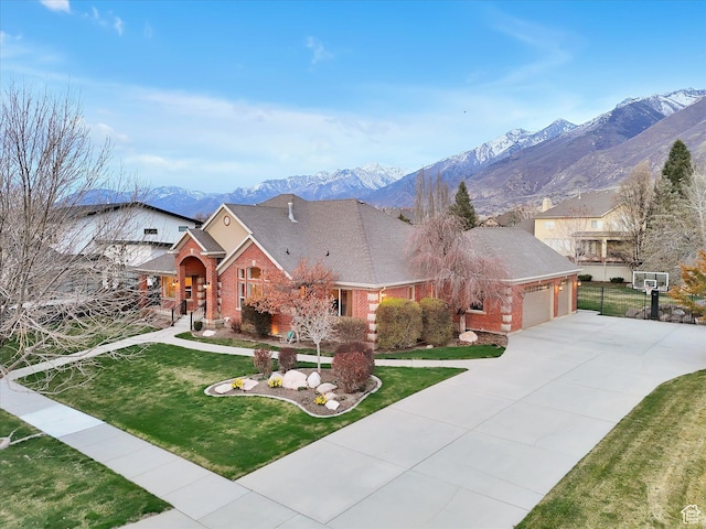 view of front of house with a front yard, a garage, brick siding, a mountain view, and concrete driveway