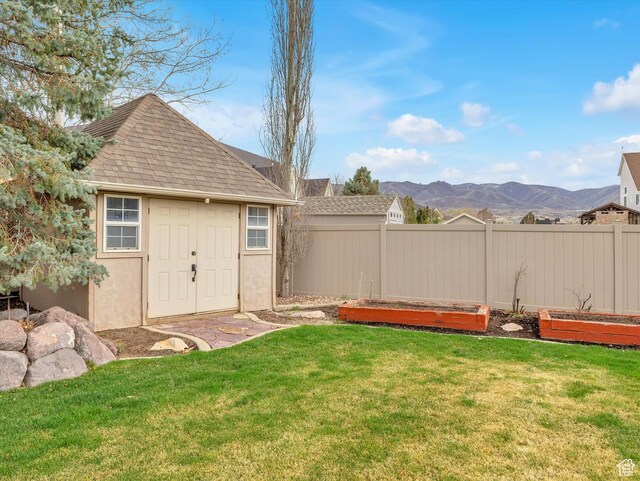 view of yard with an outbuilding, a vegetable garden, fence, a mountain view, and a storage unit