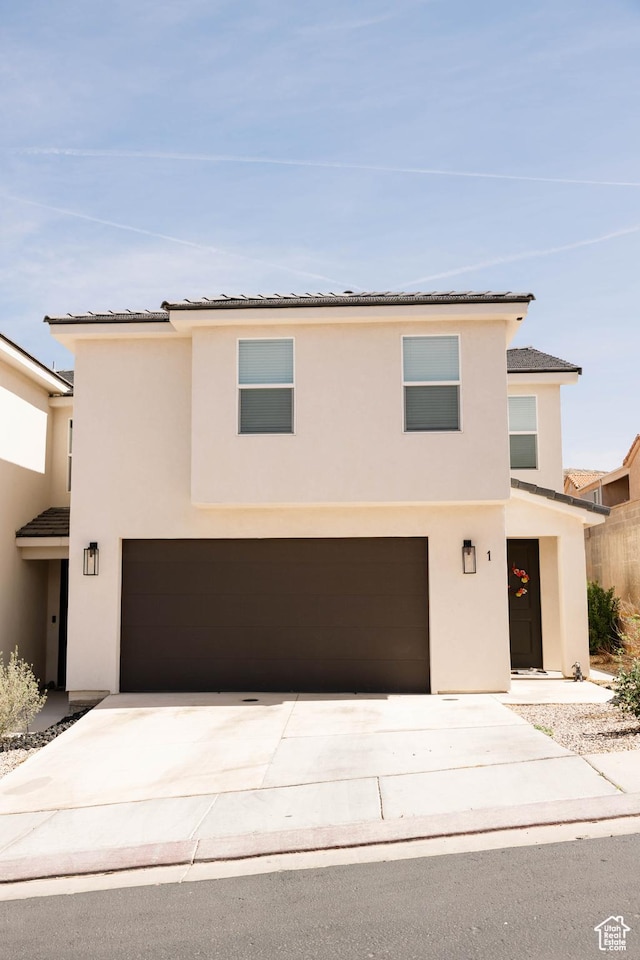 view of front of house featuring a tiled roof, stucco siding, an attached garage, and concrete driveway