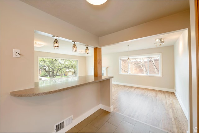 kitchen with baseboards, pendant lighting, tile patterned flooring, and light stone counters