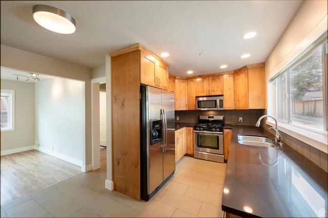 kitchen with appliances with stainless steel finishes, a sink, tasteful backsplash, dark countertops, and recessed lighting