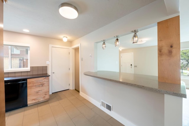 kitchen featuring black dishwasher, light tile patterned floors, stone countertops, baseboards, and a peninsula