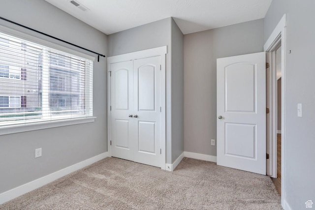 unfurnished bedroom featuring light carpet, a closet, and baseboards