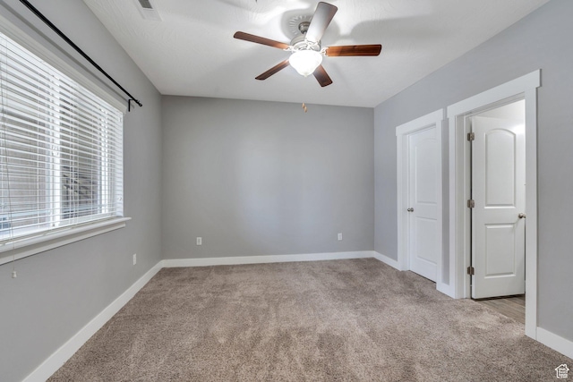 carpeted empty room featuring ceiling fan and baseboards