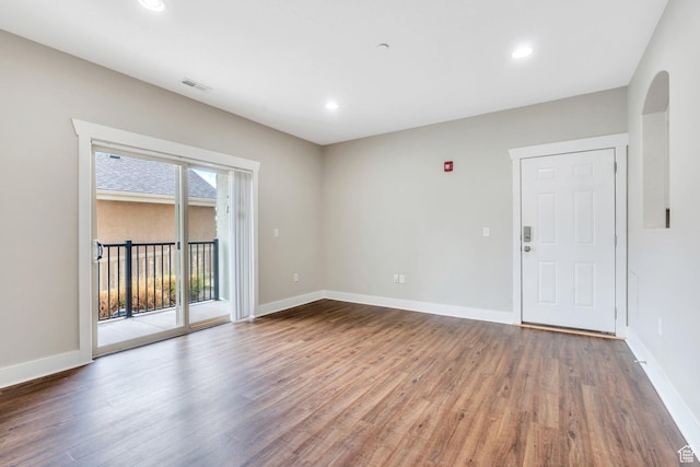 empty room with wood finished floors, baseboards, arched walkways, and recessed lighting
