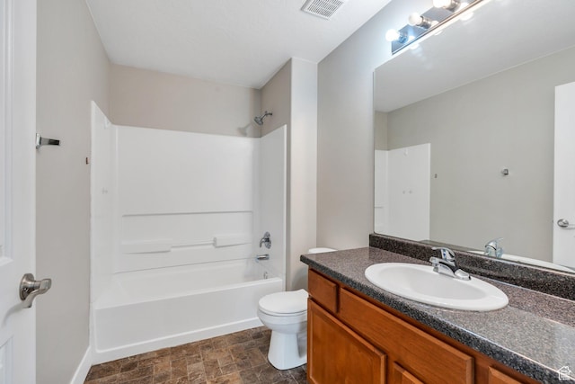 full bathroom featuring toilet, vanity, washtub / shower combination, stone finish flooring, and baseboards