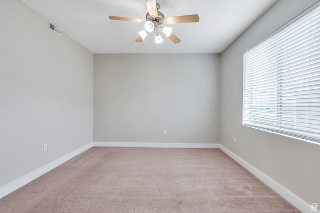 spare room with light colored carpet, ceiling fan, and baseboards