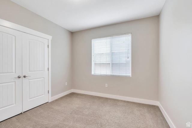 unfurnished bedroom featuring carpet flooring, baseboards, and a closet