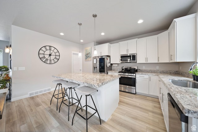 3724 E Long Ridge Dr, Eagle Mountain, UT 84005 - kitchen featuring stainless steel appliances, a kitchen island, a sink, light wood-style floors, and visible vents