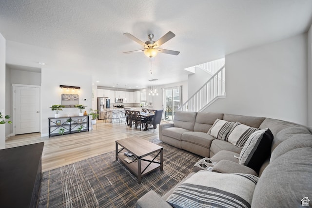 3724 E Long Ridge Dr, Eagle Mountain, UT 84005 - living room with light wood-style floors, a textured ceiling, stairway, and ceiling fan with notable chandelier