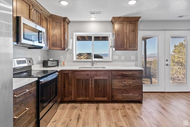 14440 N 11740 E, Mount Pleasant, UT 84647 - kitchen featuring appliances with stainless steel finishes, a sink, light countertops, light wood-type flooring, and a textured ceiling