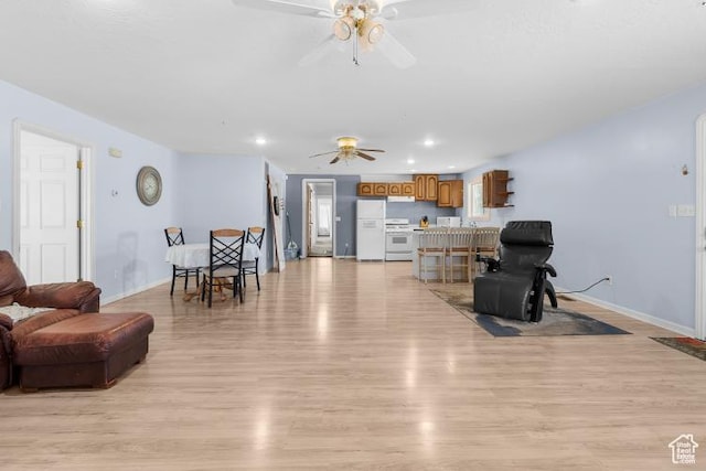 living room with baseboards, light wood-style floors, ceiling fan, and recessed lighting