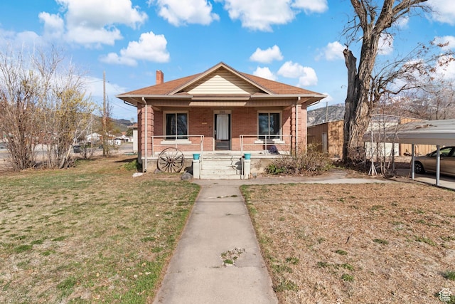 bungalow-style house with a chimney, brick siding, a porch, and a front lawn