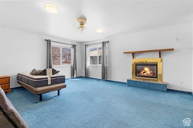 sitting room featuring baseboards, carpet flooring, and a glass covered fireplace