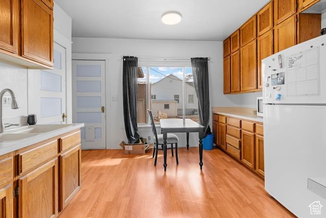 kitchen featuring light countertops, a sink, light wood-style floors, and freestanding refrigerator