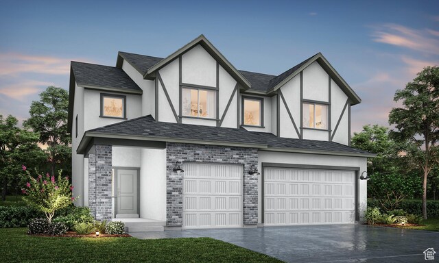 tudor-style house with driveway, stucco siding, an attached garage, and stone siding