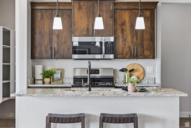 1867 W Grapevine, Hurricane, UT 84737 - kitchen featuring appliances with stainless steel finishes, a kitchen island with sink, dark brown cabinetry, and a breakfast bar
