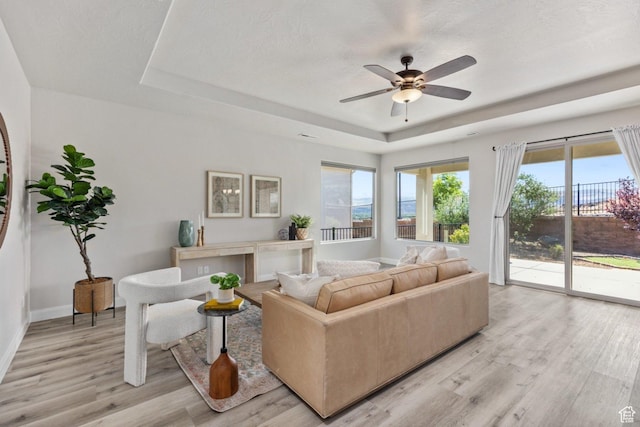 1867 W Grapevine, Hurricane, UT 84737 - living room featuring a tray ceiling, light wood-style floors, a ceiling fan, and baseboards