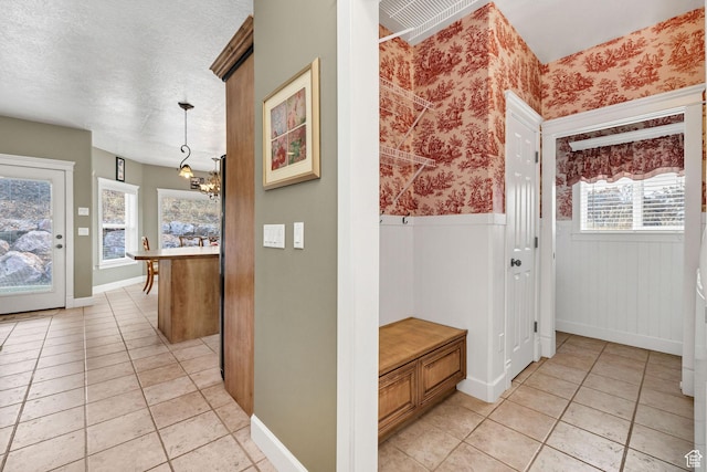 240 Bugle Way, Providence, UT 84332 - hallway featuring a wainscoted wall, a textured ceiling, wallpapered walls, an inviting chandelier, and light tile patterned floors