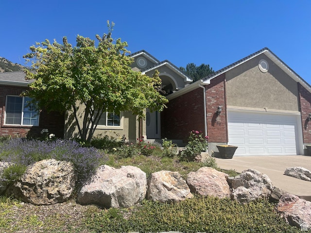 240 Bugle Way, Providence, UT 84332 - view of front of home featuring concrete driveway, a garage, brick siding, and stucco siding