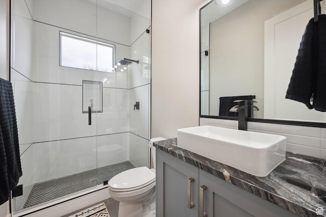 full bath featuring a stall shower, toilet, and vanity
