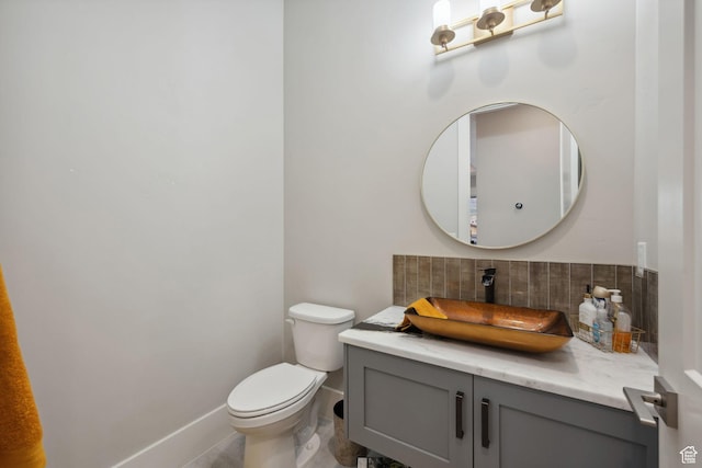 bathroom featuring toilet, vanity, tasteful backsplash, and baseboards