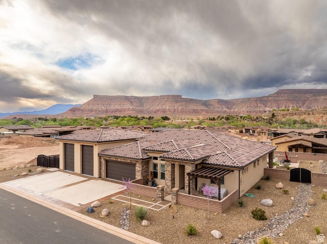 view of front of home featuring concrete driveway, stucco siding, fence, a mountain view, and a garage