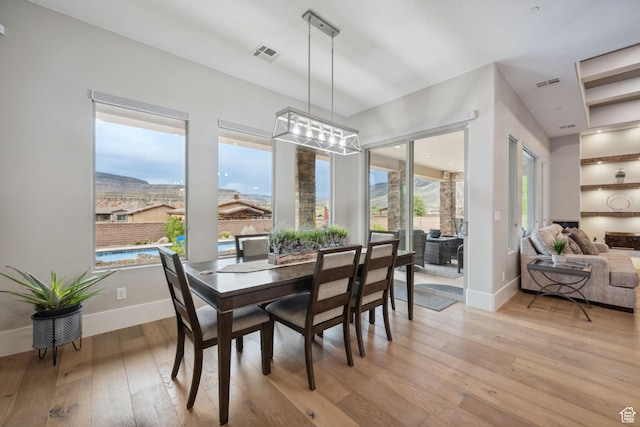 dining space featuring light wood finished floors, baseboards, and visible vents