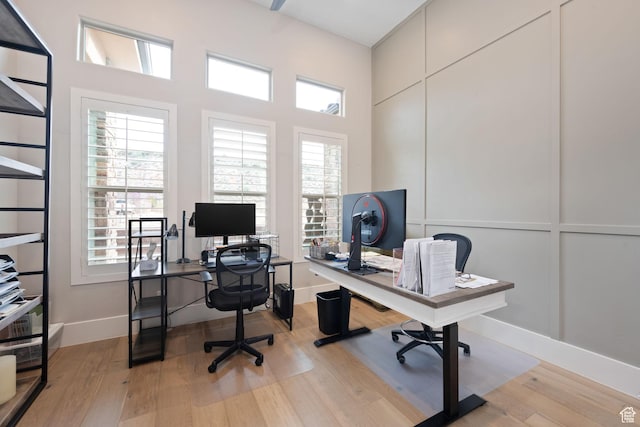 office space featuring baseboards, wood finished floors, and a decorative wall