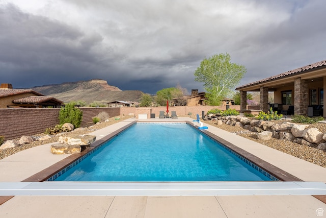 view of swimming pool with a fenced backyard, a fenced in pool, a mountain view, and a patio area