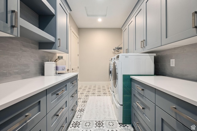 laundry room featuring attic access, washer and clothes dryer, cabinet space, and baseboards